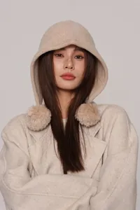 Dettaglio del passamontagna in maglia di lana beige con pompon morbidi sui lati