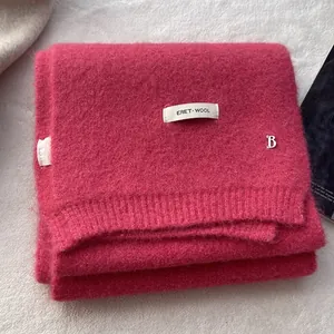 Detail of wool knit scarf featuring silver B-pendant and woven textile brand label