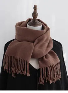 Detailed texture of thick dark coffee wool scarf with long tassel hem on a wooden hanger