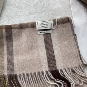 Detailopname van de wollen ruitjes sjaal met zachte franjes en geweven textiellabels