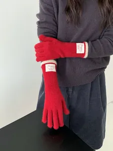 Dettaglio di guanti in maglia rossi con etichetta tessuta Bonjour bianca sul polsino in lana