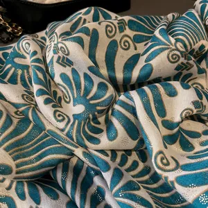 Detailed close-up of blue cotton linen scarf with golden glitter and vintage leaf pattern