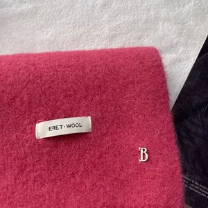 Detail of wool fabric texture with silver B logo and woven ERET WOOL label on scarf