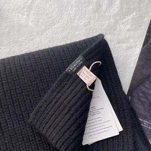Detaillierte Makroansicht von 100% reiner Wolle, schwarze Strickschal-Textur mit Etiketten