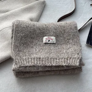 Close-up of brown wool blend knitted scarf texture with premium branded woven label