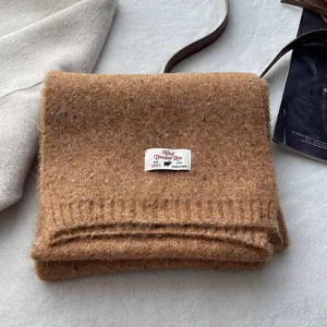 Detailed view of brown wool blend knit scarf with ribbed edges and luxury fabric label
