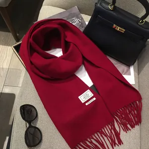 Dettaglio di sciarpa in lana rossa con frange ed etichetta autentica 100% pura lana