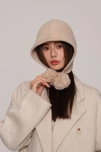 Dettaglio della maglia del passamontagna in lana beige con pompon decorativi