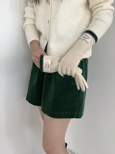 Dettaglio guanti in maglia con etichetta 'Bonjour' e polsini a coste verde scuro
