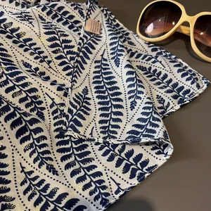 Detailed close-up of a semi-transparent scarf with blue fern leaves and gold gilding