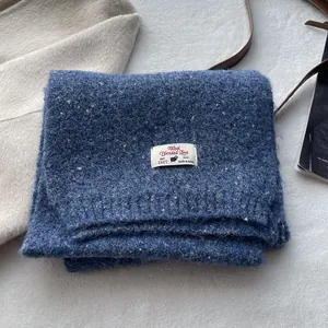 Detailed texture of thick sea salt blue wool blend knitted scarf with premium brand tag