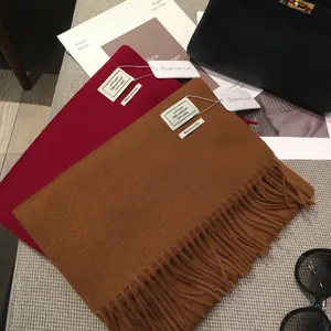 Dettaglio di sciarpe in lana rossa e cammello 100% lana con frange fini ed etichetta premium