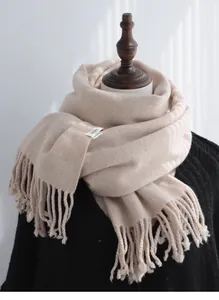 Detail of light beige 100% pure wool scarf with twisted tassels on a black sweater mannequin