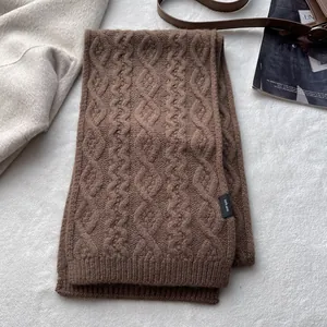 Detailed view of cable-knit 100% merino wool scarf with premium woven brand label