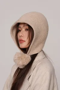 Dettaglio della balaclava in lana beige lavorata a maglia con morbido pompon