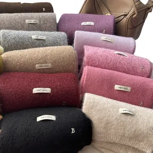 Stack of colorful knitted wool scarves with metal pendants and soft brushed texture