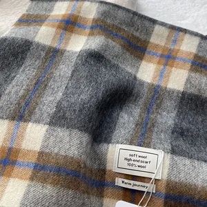 Detailed close-up of 100% wool material label on a classic plaid winter scarf