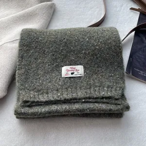 Detail of wool blend scarf featuring branded woven label and soft textured fabric