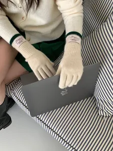 Dettaglio di guanti in maglia touch con etichetta Bonjour su un computer portatile