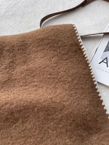 Close-up of brown plush tote bag featuring white whipstitch edges and leather straps