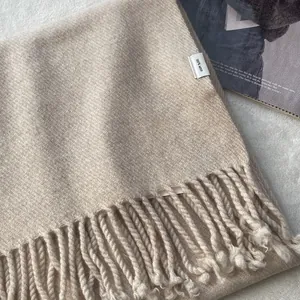 Detailed texture of 100% wool scarf with soft fringe and fine woven fabric in beige