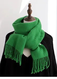 Detail of pure wool scarf in grass green with soft knitted texture and dense fringe edges