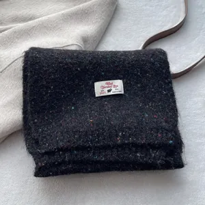 Detail of wool blend scarf featuring colorful neps and woven brand label in black