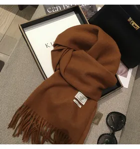 Dettaglio della sciarpa color caramello in simil-cashmere con frange ed etichetta