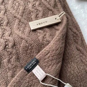 Detail of 100% Merino wool scarf with cable knit texture and premium wash label