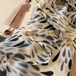 Detail of silk-like printed scarf featuring gold metallic accents and soft drapery