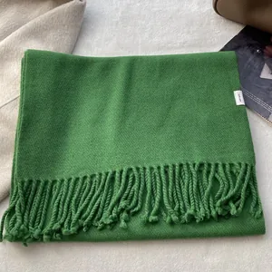 Detailed view of 100% pure wool green scarf with twill weave texture and fringe edges