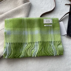 Close-up of green and grey check 100% wool scarf with fringe and woven label detail