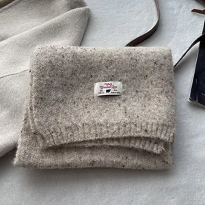 Close-up of oatmeal wool blend scarf texture with premium branded woven label details