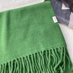 Detail of 100% pure wool green scarf showing thick woven texture and fringed edges
