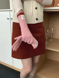 Dettaglio guanti in maglia rosa con bordo rosso ed etichetta Bonjour per l'inverno