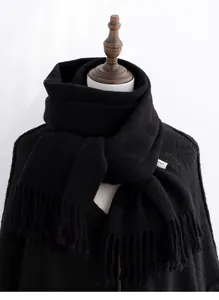 Close-up of black 100% pure wool scarf with tassel edges and white material label