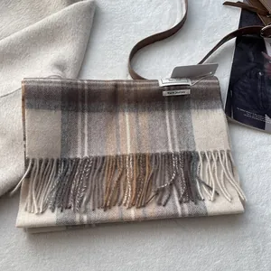 Detail showing the 100% wool label and fringe texture of the classic plaid scarf