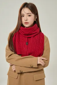 Detailed macro view of red cable knit wool scarf with 100% wool material label
