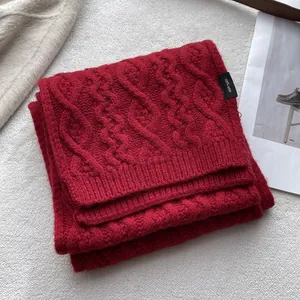 Detail of red cable knit 100% merino wool scarf showcasing thick texture and soft material