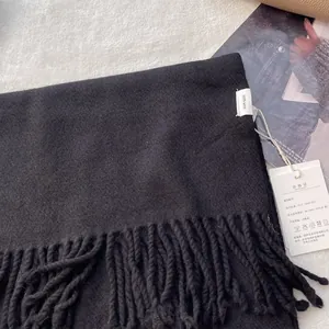 Detail of black 100% pure wool scarf featuring handmade tassels and official care labels