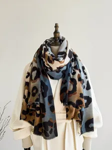 Detailed texture of leopard print scarf with blue and brown tassels on a white coat