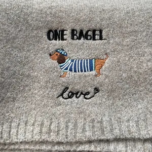 Close-up of cute dachshund embroidery with One Bagel text on grey knitted scarf