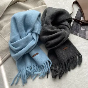Detail of soft knit wool scarves in light blue and grey with fringe and leather tags
