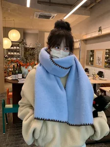 Close-up of sky blue wool scarf with dark brown contrast stitching detail on the edge