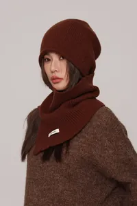 Close-up of dark brown wool knit beanie showing ribbed texture and 100% wool material label