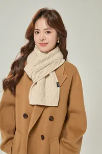 Detail of chunky cable knit cream scarf with 100% wool label on beige wool coat
