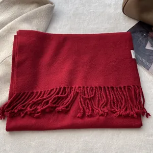 Close-up of deep red wool scarf with fringe detail and authentic material label