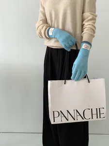 Dettaglio di guanti in maglia azzurra con patch Bonjour e funzione touch screen