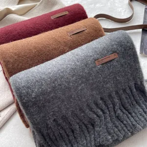 Detail of wool scarves with tassels and leather labels in red, brown, and grey colors