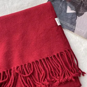 Detailed view of red 100% pure wool scarf texture with classic tassel edges and material label